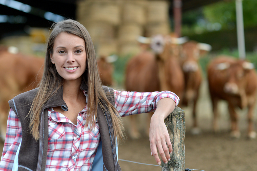 Smiling farmer woman standing by cattle outside